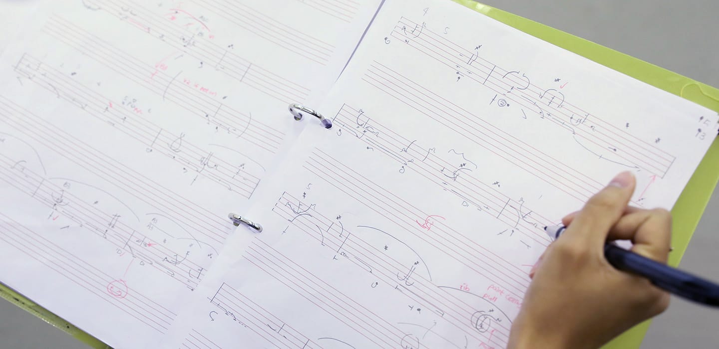 Open notebook with benesh notation and a student writing in the sheet